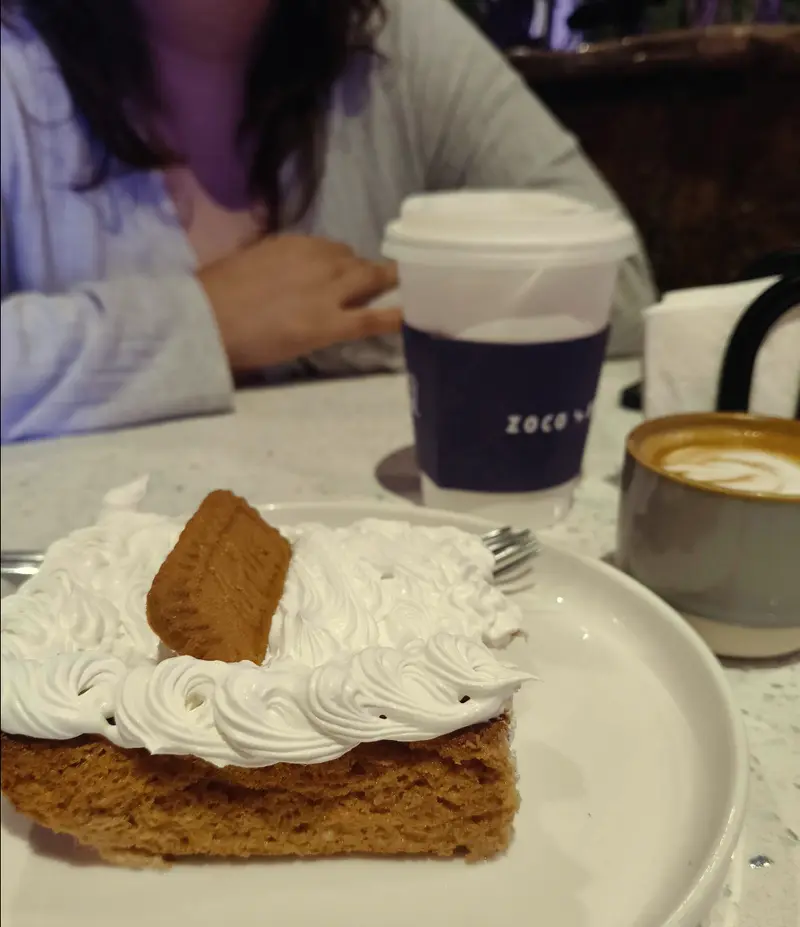 Pastel con merengue y galleta Lotus junto a un latte